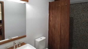 Un baño con lavamanos blanco, inodoro y cabina de ducha de madera.