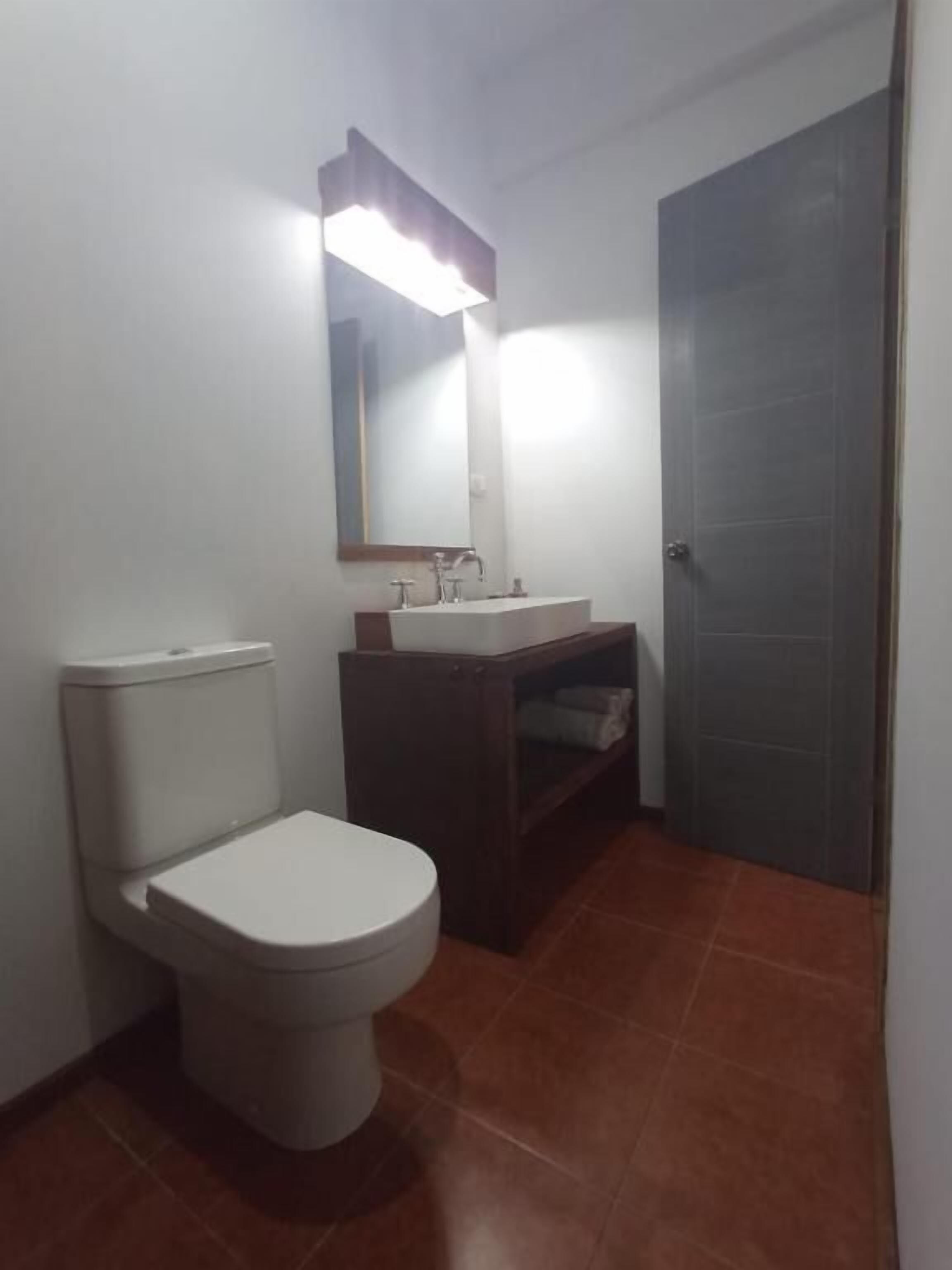 A small bathroom with a toilet, a sink, and a mirror.