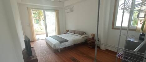 A bedroom with a bed, a ceiling fan, a window, and a metal rack.