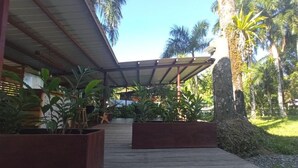 Un espacio al aire libre cubierto con suelo de madera, plantas en macetas y un árbol grande.