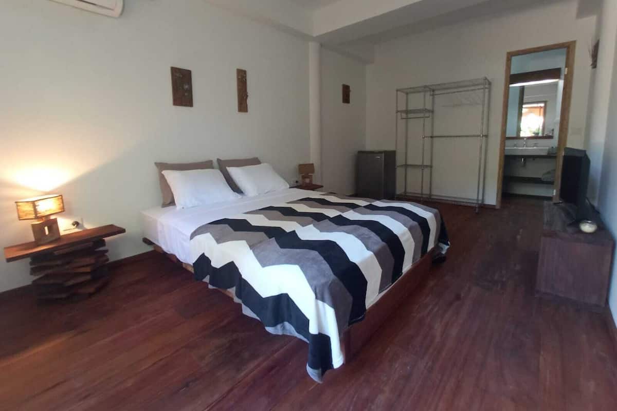 A bedroom with a bed, bedside tables, a wardrobe, and a mirror.