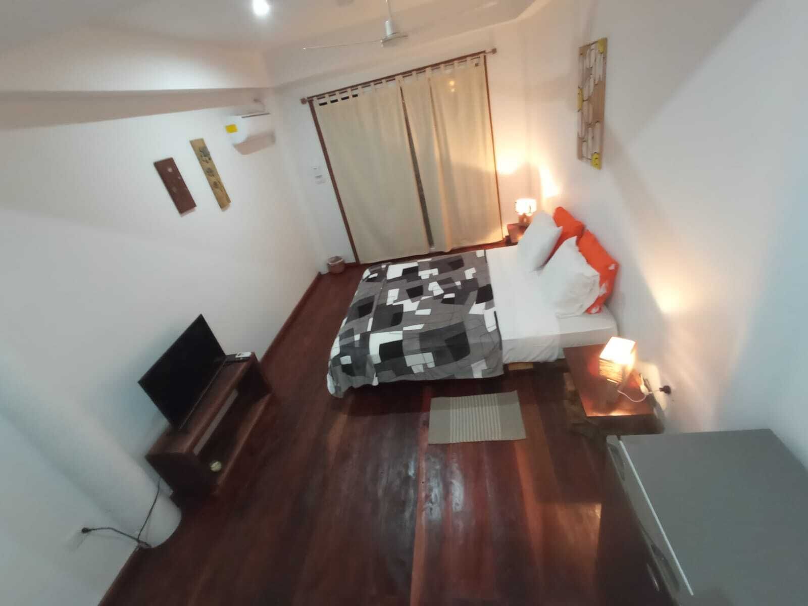 Ein Schlafzimmer mit Bett, Nachttisch, Lampe und Schreibtisch mit Stuhl.