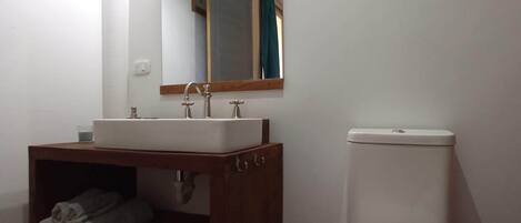 Un baño con un lavabo blanco, un espejo encima, un inodoro y un perchero con toallas.