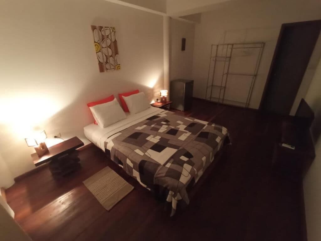 Une chambre à coucher comprenant un lit, des tables de chevet, un tapis et une œuvre d’art accrochée au mur.
