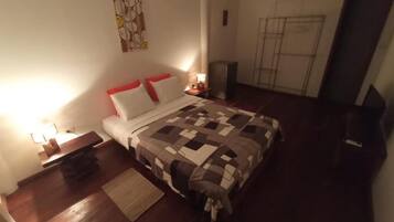 Une chambre à coucher comprenant un lit, des tables de chevet, un tapis et une œuvre d’art accrochée au mur.