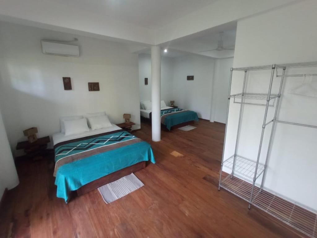 A hotel room with two beds, a metal rack, and a wooden floor.