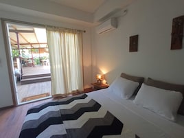Habitación de hotel con una cama, una mesita de noche con lámpara, una ventana con cortinas y un equipo de aire acondicionado.