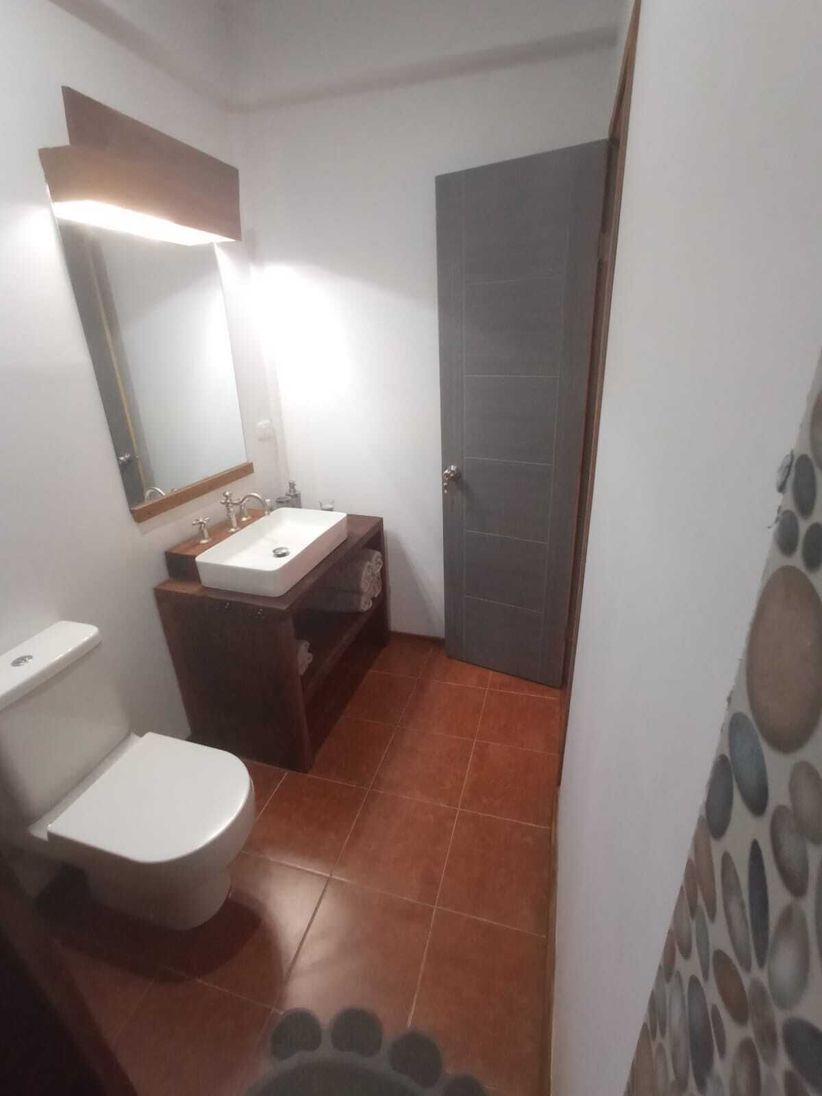 A small bathroom with a toilet, sink, and mirror.