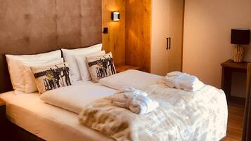 A modern hotel room with a large bed, wooden headboard, a wardrobe, and a bedside lamp.