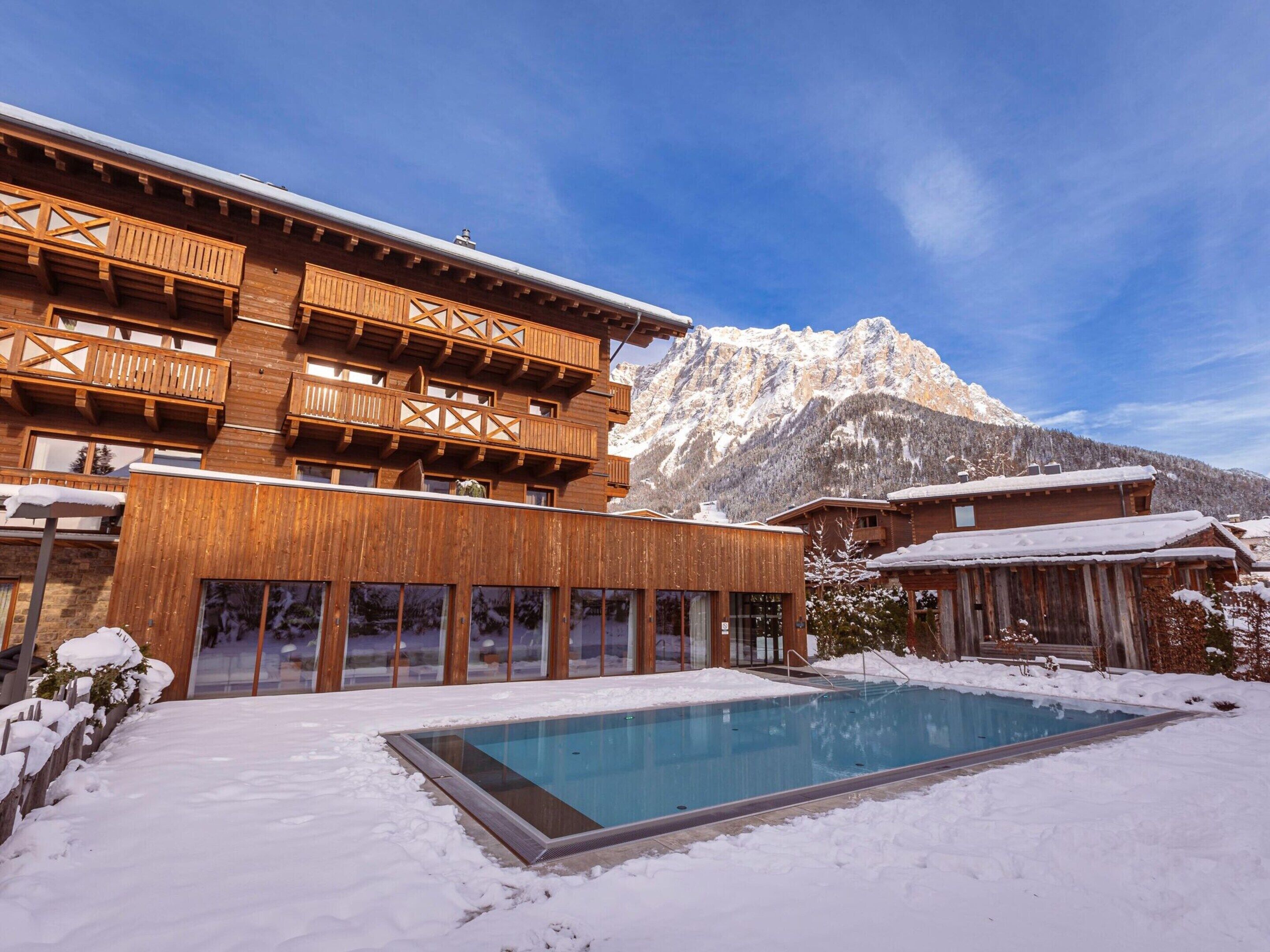 A wooden building with balconies and a pool in a snowy setting.