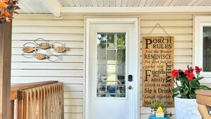 Una puerta principal con un felpudo que dice "Larry's Lodge" y un letrero en la pared que dice "NORMAS DEL PORCHE".
