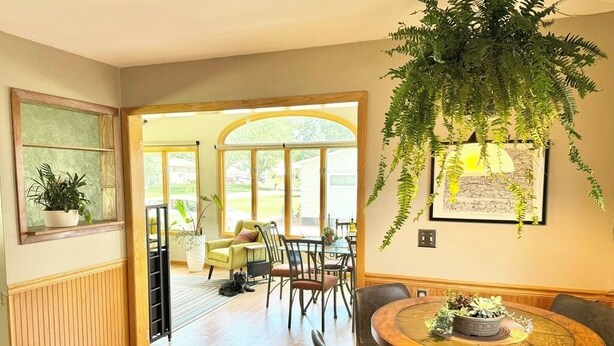 Un comedor con una mesa redonda de madera, sillas negras y una planta colgante.