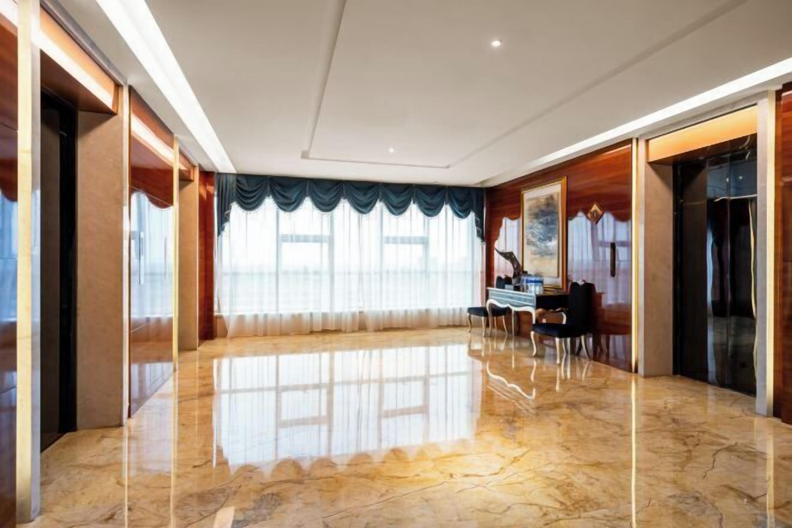 A spacious room with a polished marble floor, a piano, and a large window with curtains.