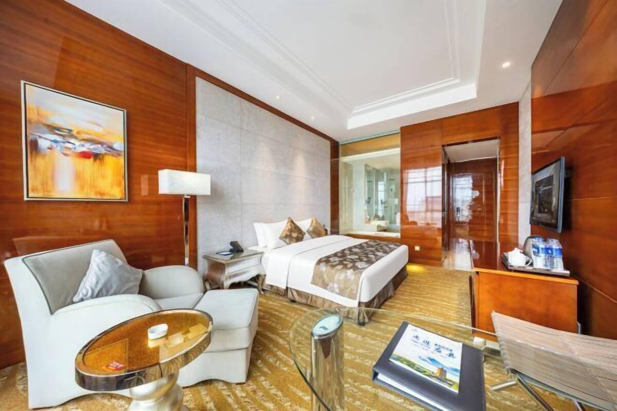 Une chambre d’hôtel comprenant un lit, un canapé, une table basse, une télévision et un bureau avec une lampe.