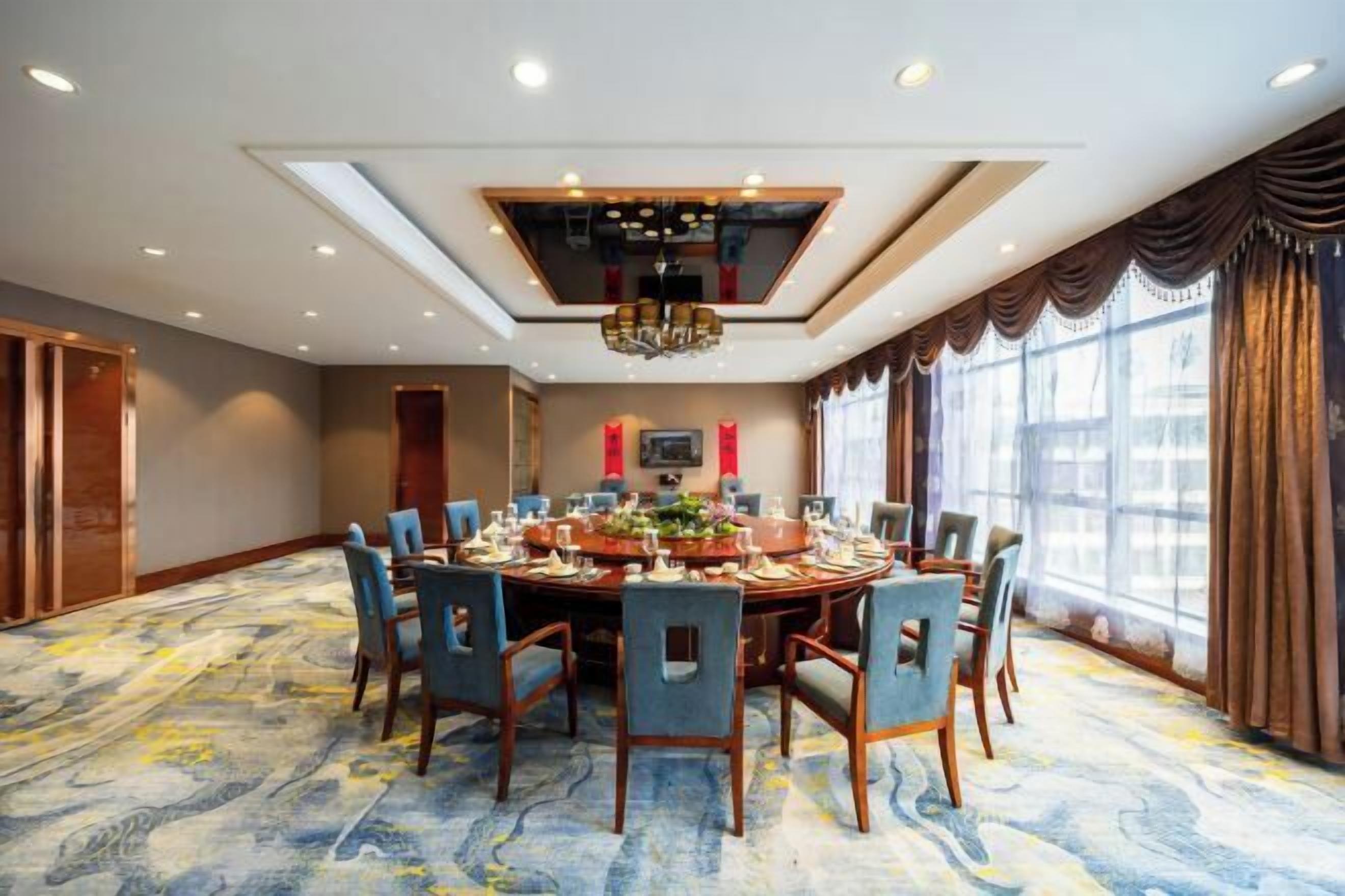 A conference room with a round table, chairs, and a chandelier.