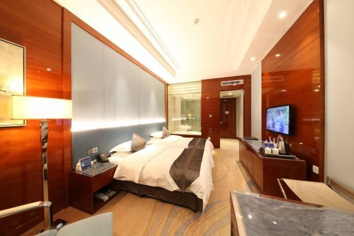 Une chambre d’hôtel avec un grand lit, un bureau avec un ordinateur, une télévision et un minibar.