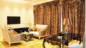 Un salon luxueux doté d’un grand téléviseur à écran plat, d’un mobilier élégant et d’un tapis à motifs.