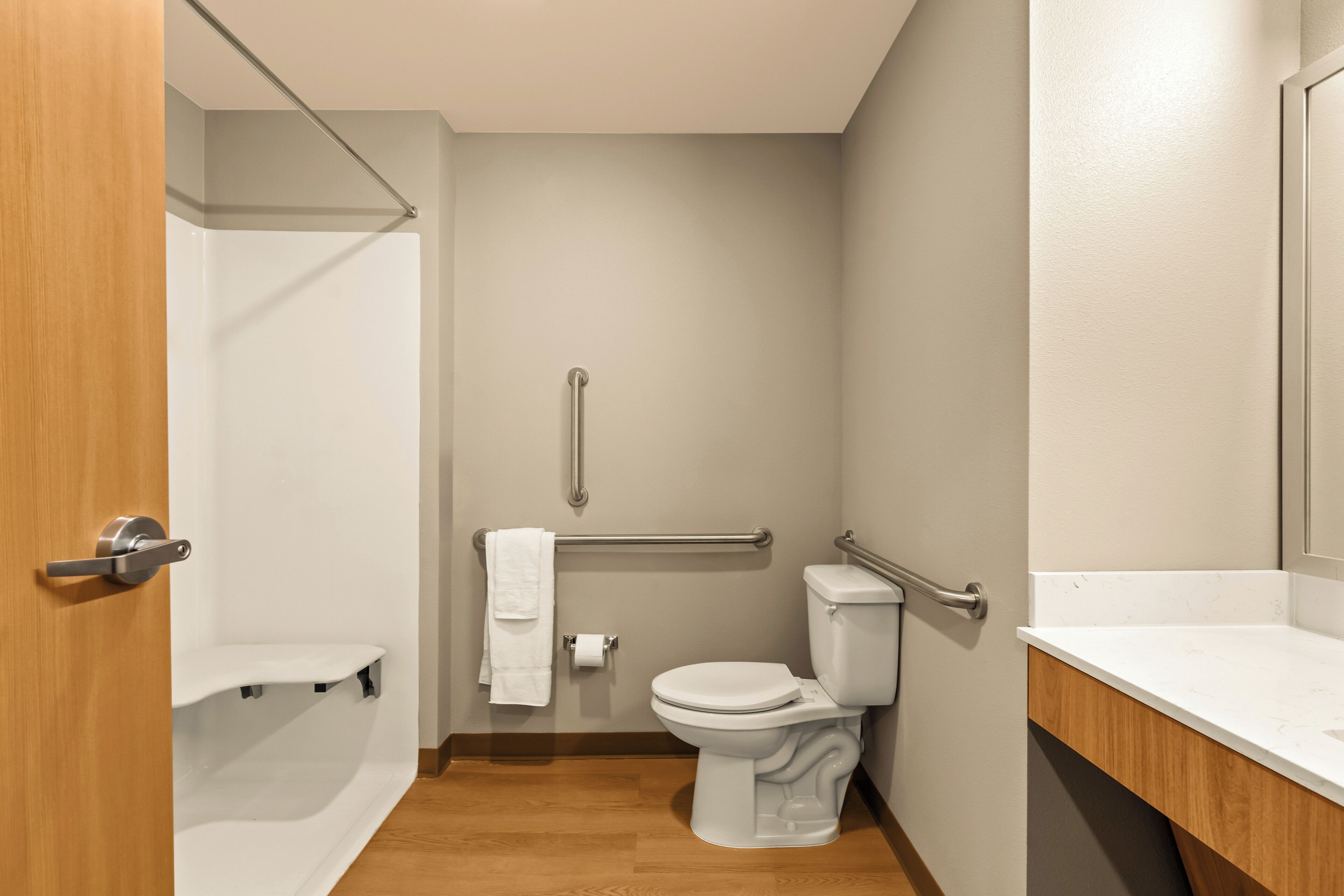 Une petite salle de bain moderne avec des toilettes blanches, un espace douche et un meuble-lavabo en bois.
