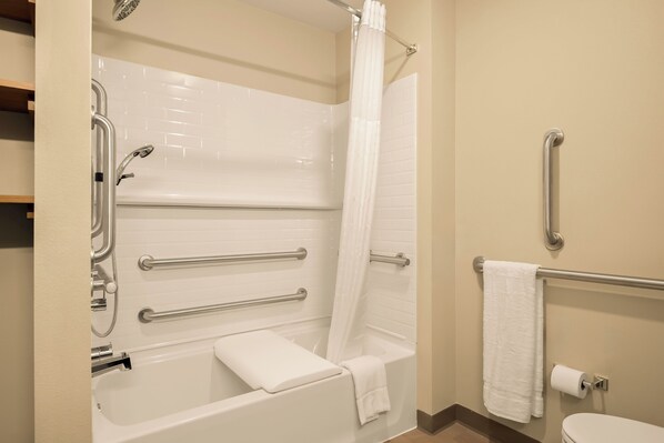 Un baño con bañera, barras de apoyo, ducha, toallero y retrete.