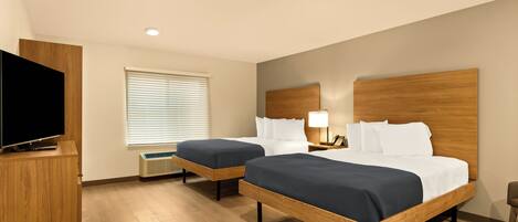 Une chambre d’hôtel avec deux lits, une télévision et une fenêtre avec des stores.