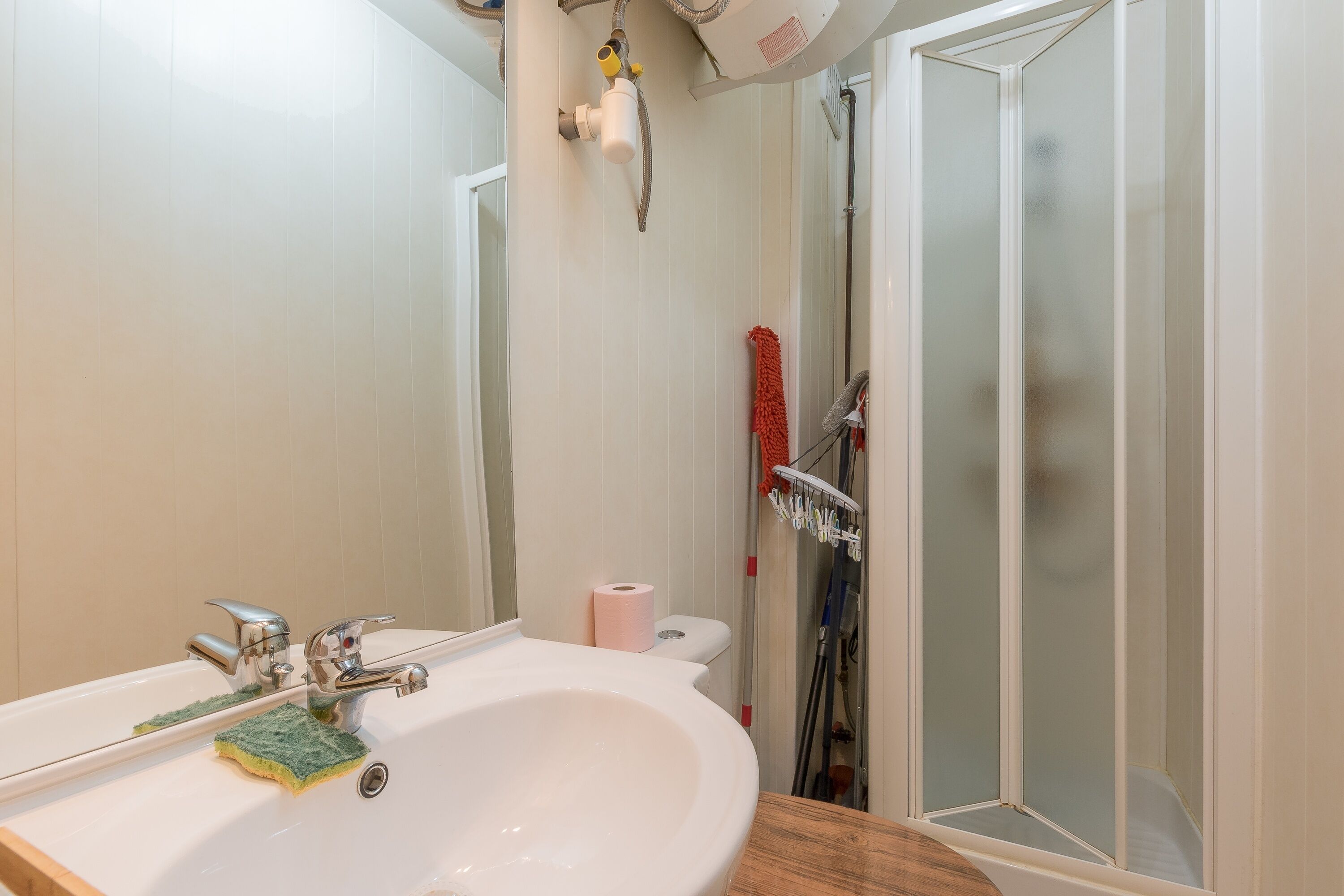 Une salle de bain équipée d’un lavabo, d’un miroir, d’une douche et de toilettes.