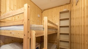 Ein Zimmer mit einem Holzbett mit zwei Etagen, einem Regal und einem kleinen Schreibtisch.