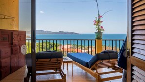 Ein Balkon mit Meerblick, Holzmöbeln und einem Blumentopf.