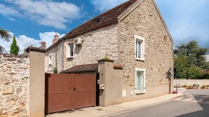 A stone building with a brown gate, a small window, and a stone wall. - Gîte du Clocher - Appt 6p avec terrasse (Moissy-Cramayel)