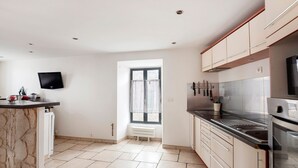 A modern kitchen with a marble countertop, stainless steel appliances, and a window with curtains. - Gîte du Clocher - Appt 6p avec terrasse (Moissy-Cramayel)