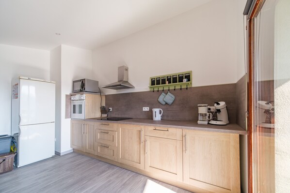 A compact kitchen with a refrigerator, microwave, oven, and a coffee maker on the counter.