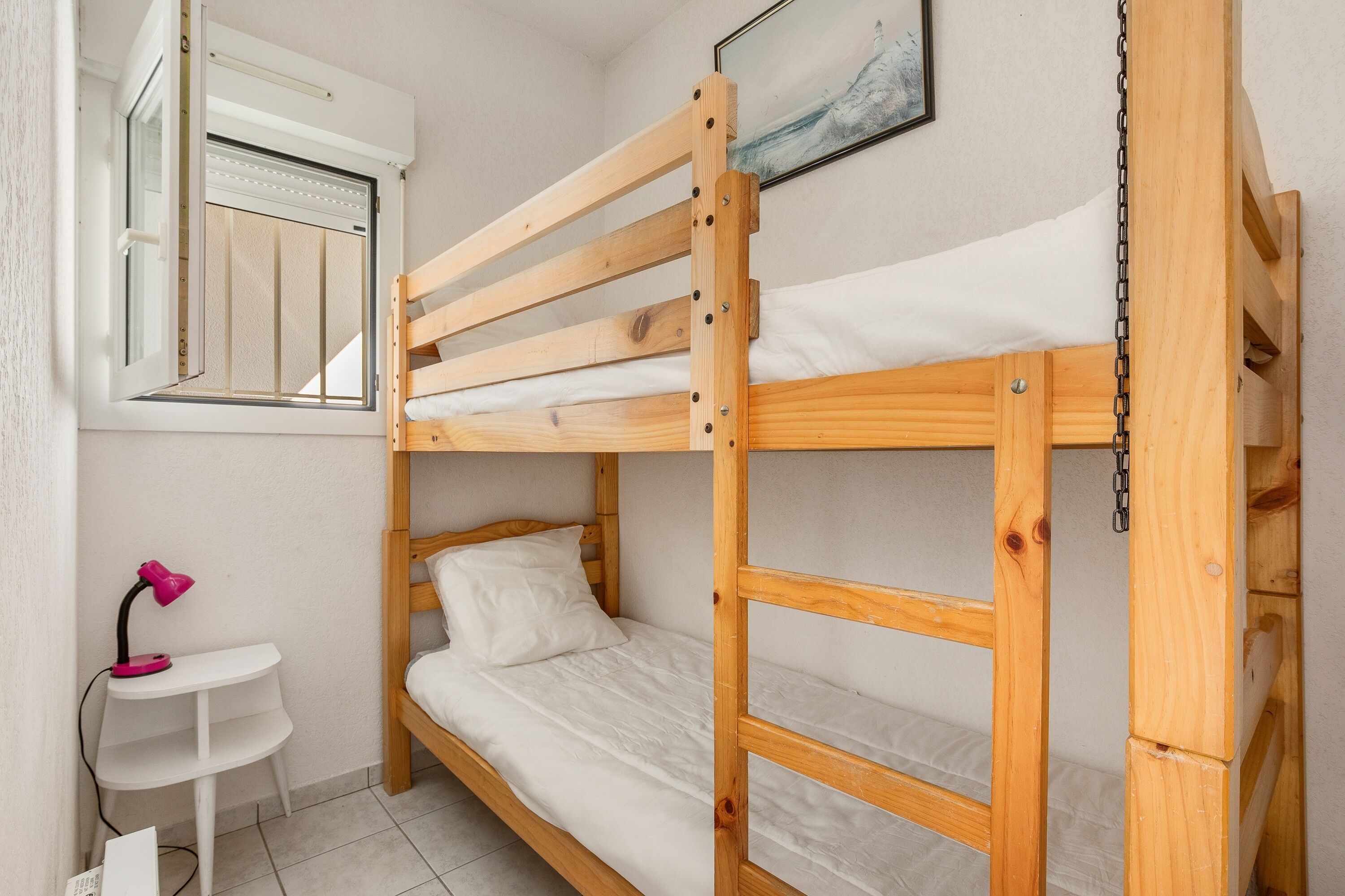 A bunk bed room with a small desk and a window.