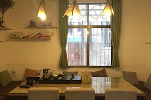 A dining area with a table, chairs, a window with curtains, and hanging lamps. - Zhangjiajie Cloud Youth Hostel (Zhangjiajie)