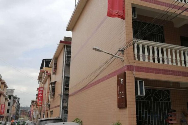A multi-story residential building with balconies, a streetlight, and a gated entrance.
