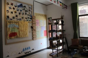 A room with a bulletin board filled with notes and photos, a bookshelf, and a window with curtains. - Zhangjiajie Cloud Youth Hostel (Zhangjiajie)
