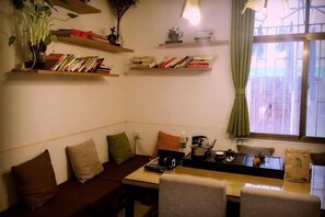 Ein gemütliches Wohnzimmer mit einer Couch, einem Tisch und Regalen mit Büchern und Dekoration.