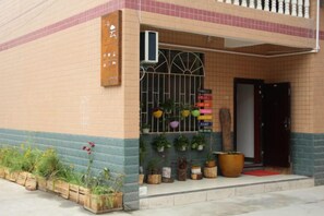 A building with a tiled facade, a gated entrance, and potted plants outside. - Zhangjiajie Cloud Youth Hostel (Zhangjiajie)