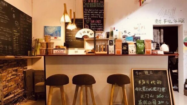 A bar area with stools, a chalkboard menu, and various beverages.