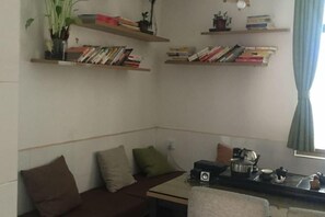 A corner room with a sofa, a small table, and a bookshelf with books. - Zhangjiajie Cloud Youth Hostel (Zhangjiajie)