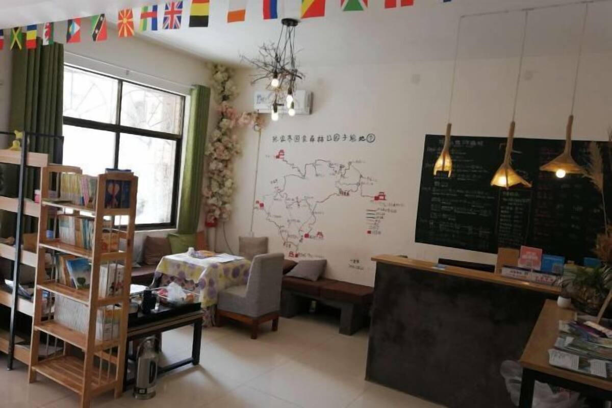 Una habitación acogedora con una estantería, un escritorio, un mapa en la pared y una ventana con cortinas.