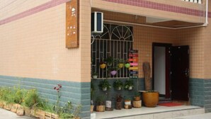 A building with a tiled facade, a metal gate, and various potted plants.