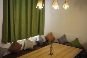 A room with a wooden table, green curtains, and a bench with cushions. - Zhangjiajie Cloud Youth Hostel (Zhangjiajie)