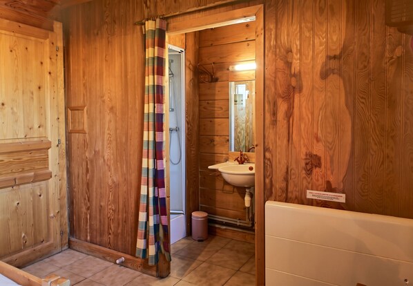 A wooden bathroom with a shower curtain, a sink, and a mirror.