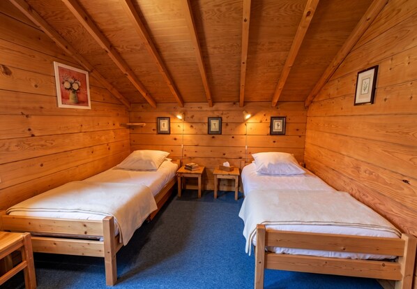 Una cabaña con dos camas de madera, una mesita y cuadros enmarcados en las paredes.