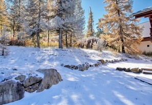 A snow-covered landscape with trees and a stone wall.