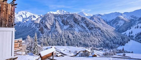 Une cabane en bois dotée d’une terrasse enneigée et offrant une vue sur la montagne.