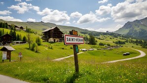 Een landelijk dorpje met een bord voor Saint-Véran, een kronkelende weg en een berg op de achtergrond.