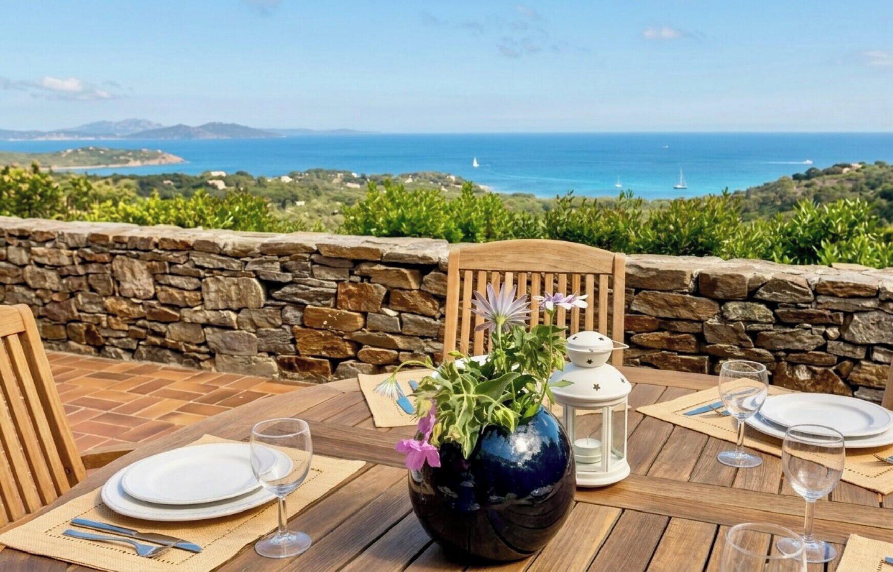 Mesa para dos con vista al mar, paredes de piedra y una silla de madera.