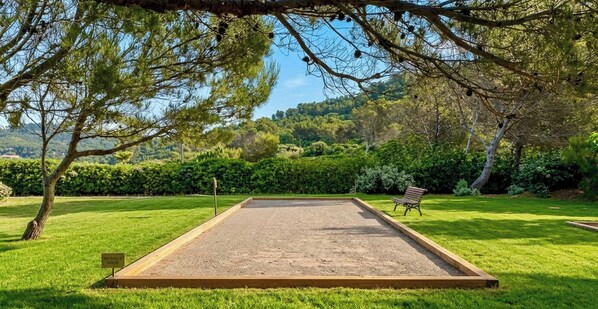 Un jardín bien cuidado con un putting green, un banco y un cartel que indica zona privada.