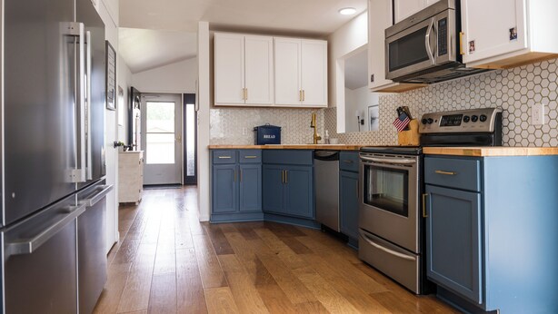 Een moderne keuken met roestvrijstalen apparatuur, blauwe kastjes en een houten aanrecht.