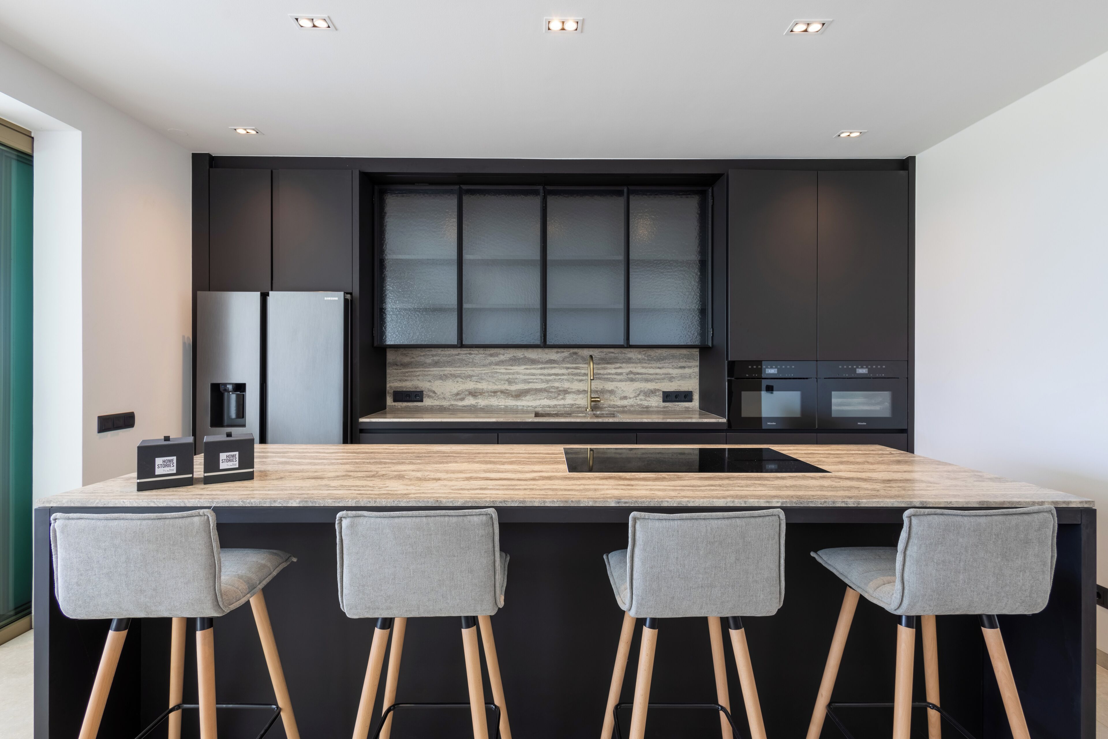 Une cuisine moderne dotée d’un îlot central, de tabourets de bar et d’appareils électroménagers intégrés.